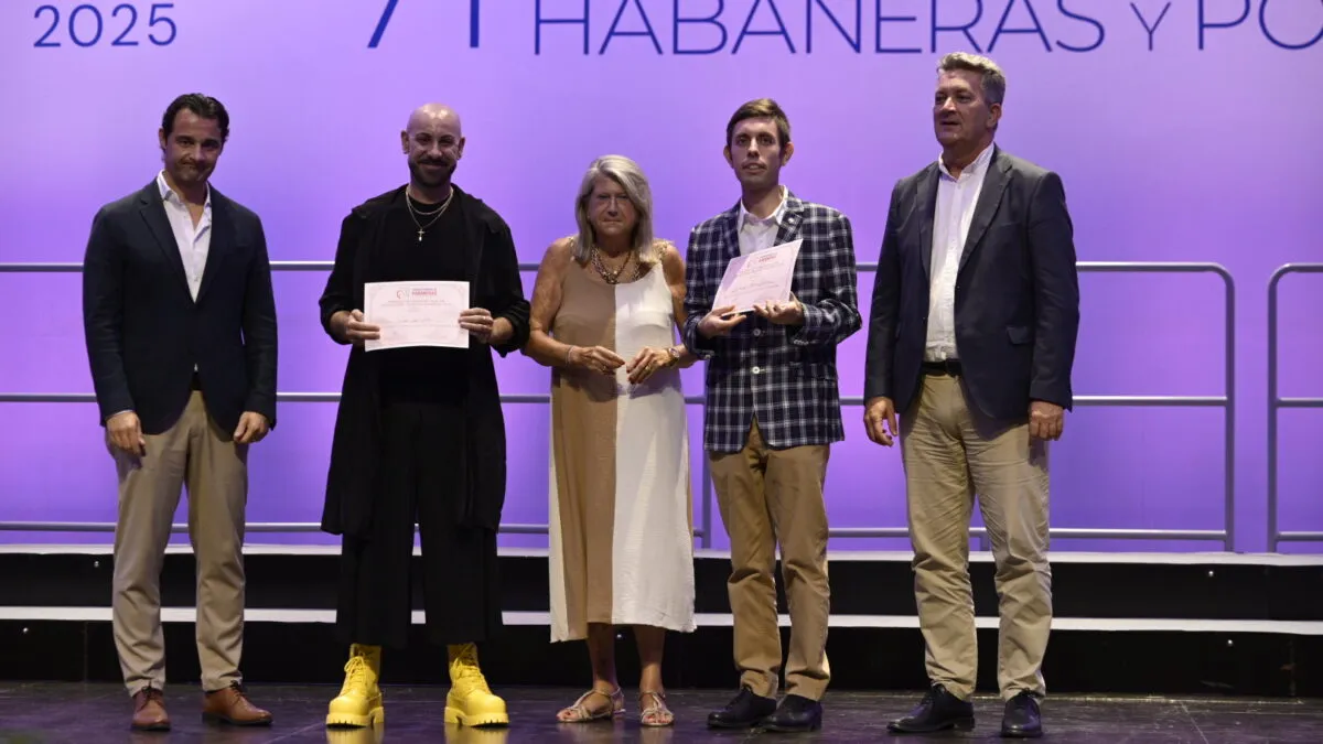 Eduardo Aranda Hortelano, con americana de cuadros, sostiene su diploma en el escenario junto a otras cuatro personas; otra de ellas también recibe diploma.